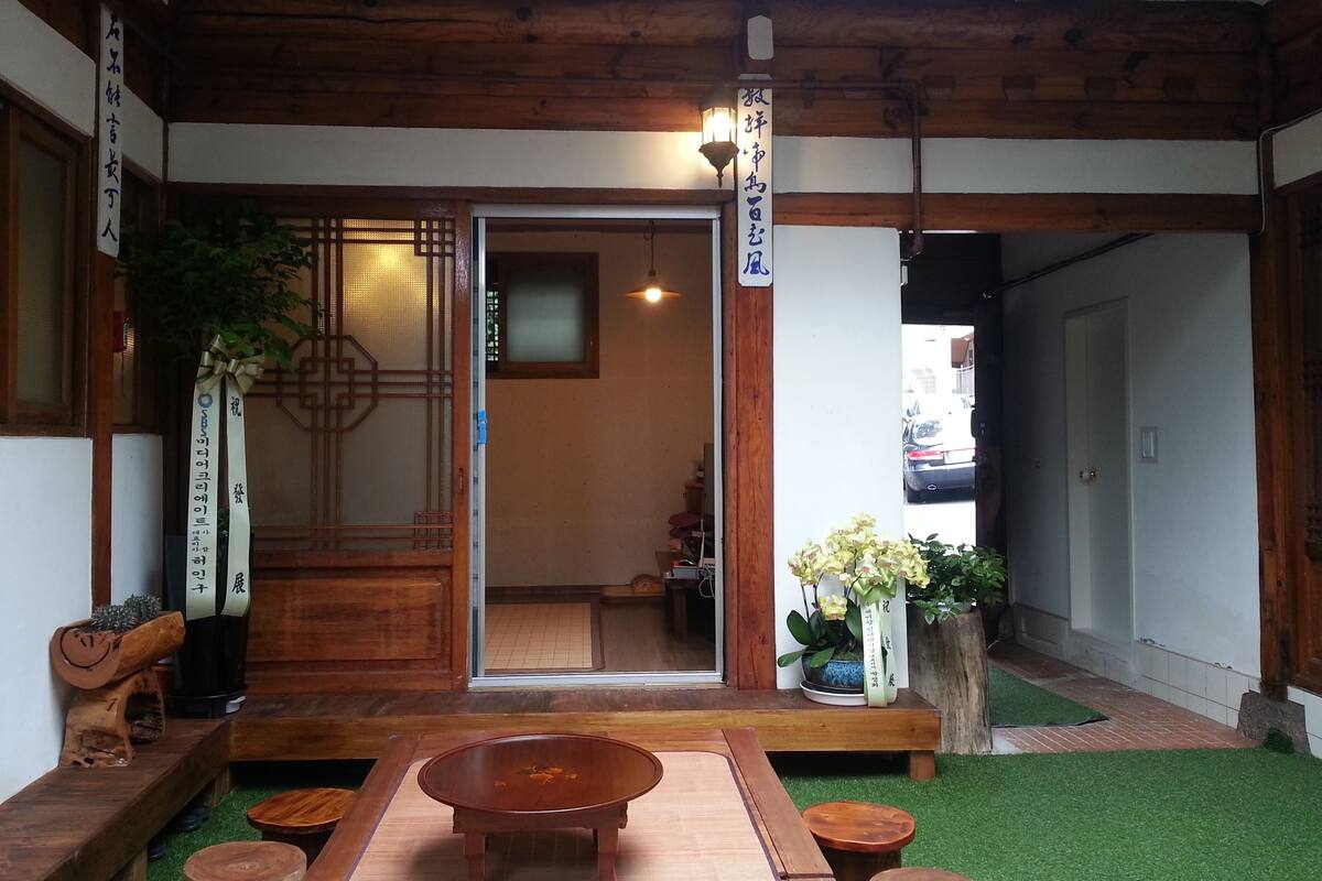 A traditional Japanese interior with tatami flooring, a wooden table, and a sliding door leading to a room.