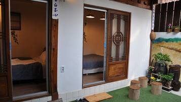 Une pièce de style japonais traditionnel, avec des portes coulissantes, un lit et un petit banc en bois à l’extérieur.