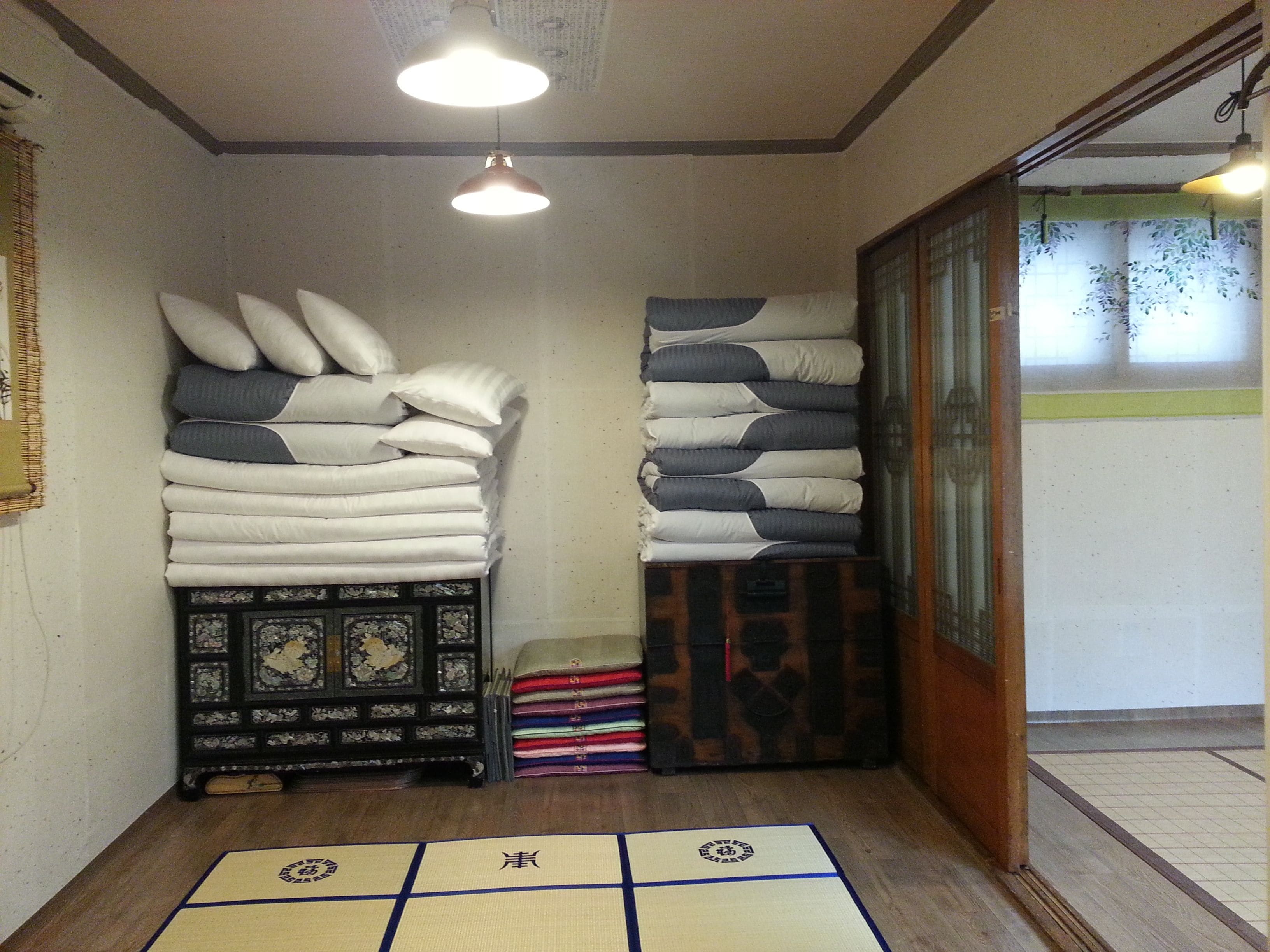 Una habitación japonesa tradicional con suelo de tatami, un montón de almohadas y un celosía de papel.