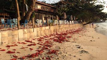 A beach with a concrete barrier, chairs, and umbrellas.