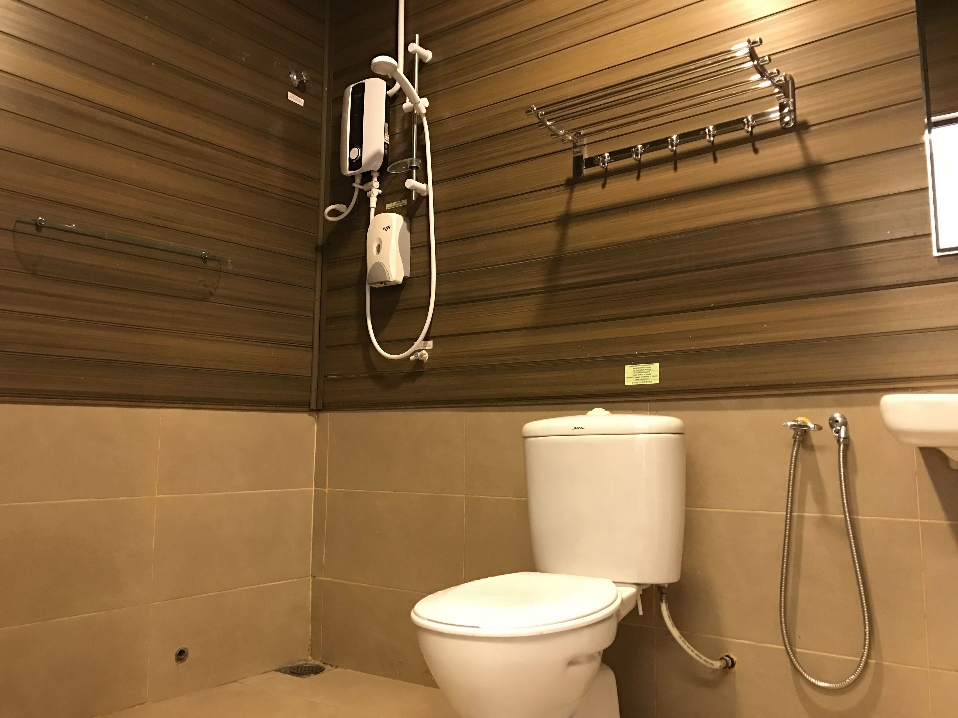 A bathroom with a toilet, a shower, and a towel rack.