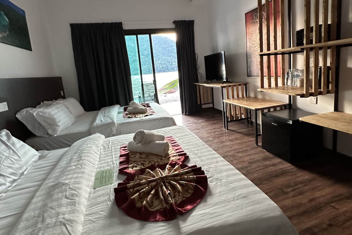 Une chambre d’hôtel avec deux lits, un bureau, une télévision et une vue sur la mer.