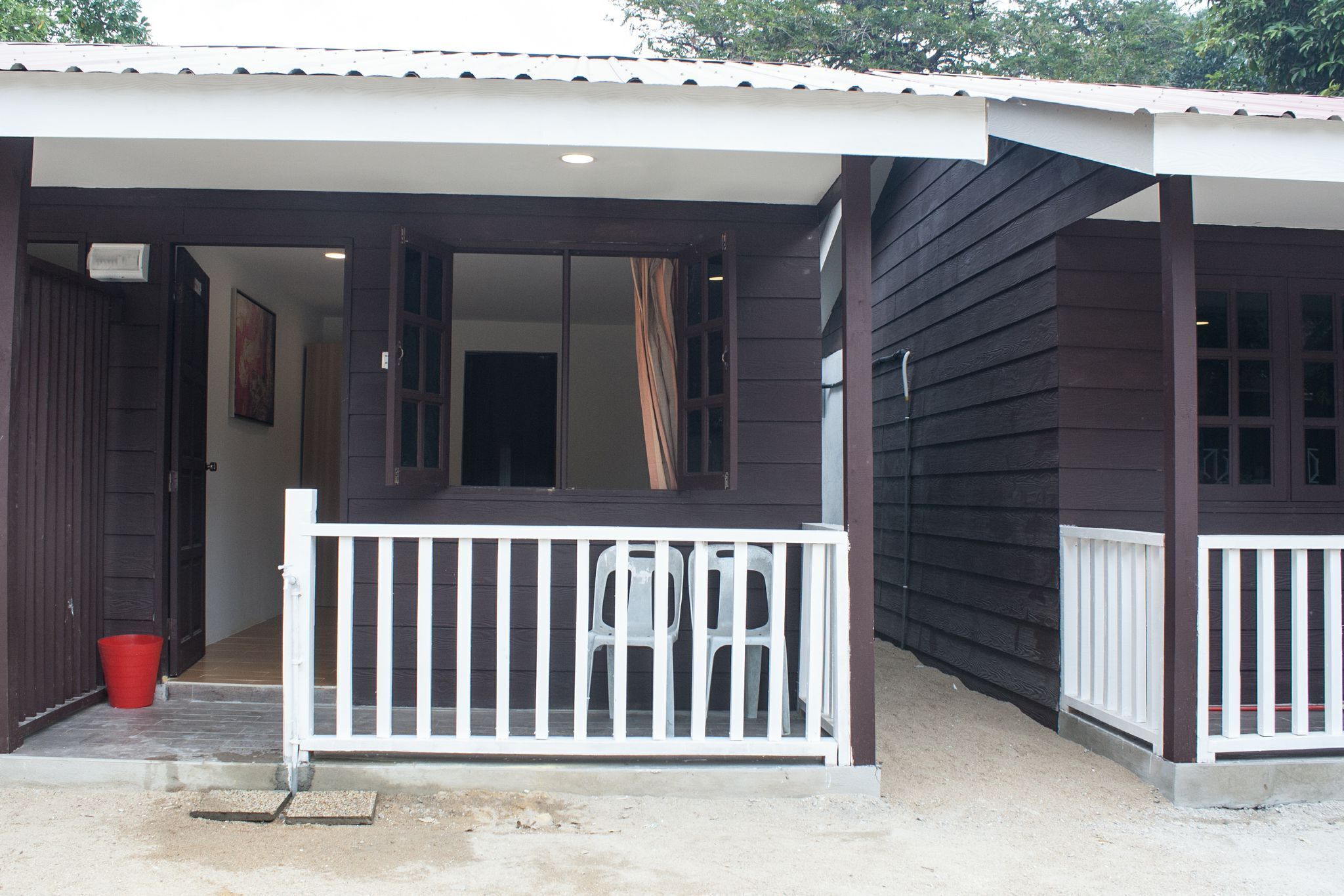 A building with a porch, a white railing, and a red bucket.
