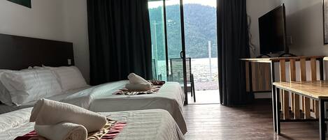 Une chambre d’hôtel avec deux lits, une télévision et vue sur la mer.