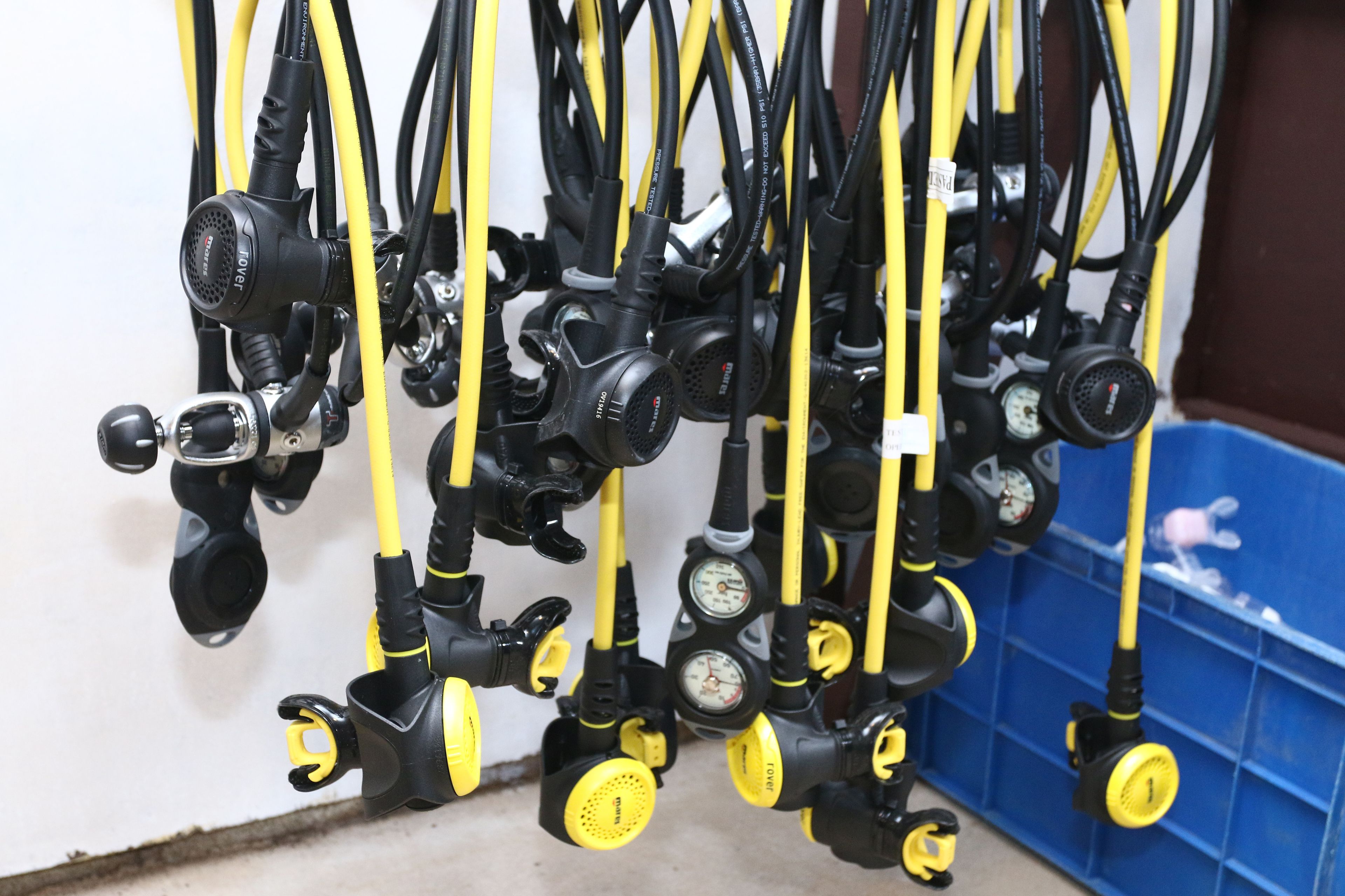 A collection of black and yellow gas regulators hanging on a wall.