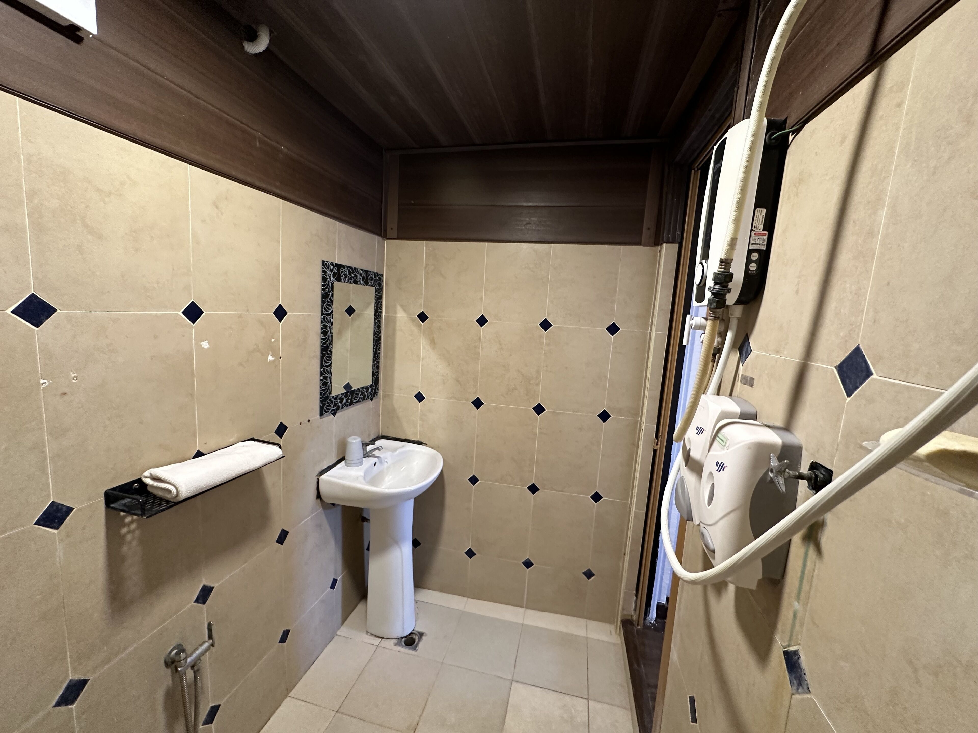 Un baño con lavamanos, espejo, toallero y zona de ducha.
