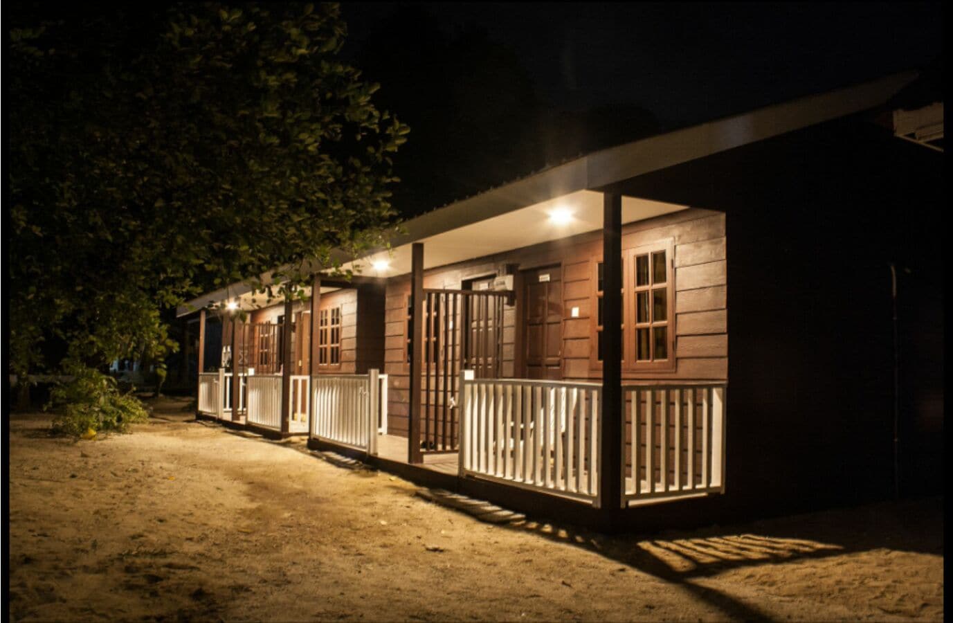 A row of cabins with wooden exteriors and white railings, connected by a covered walkway.