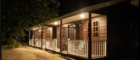 A row of cabins with wooden exteriors and white railings, connected by a covered walkway.