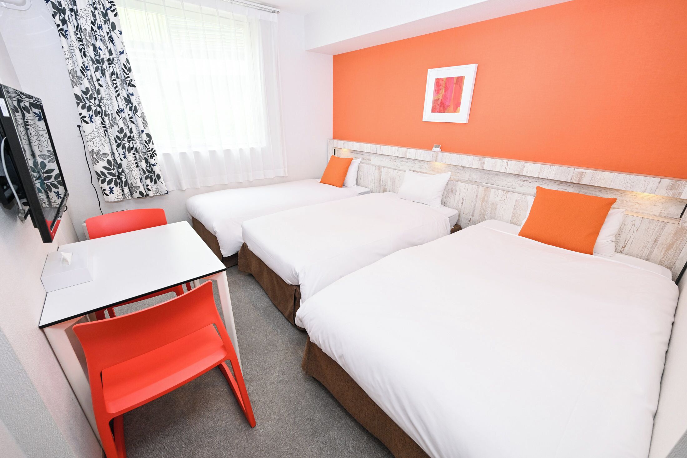 A hotel room with two beds, a desk, and a chair.
