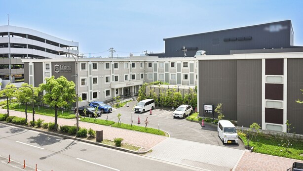 A hotel with a parking lot, multiple buildings, and a clear sky. - La'gent Hotel Osaka Bay (Osaka)