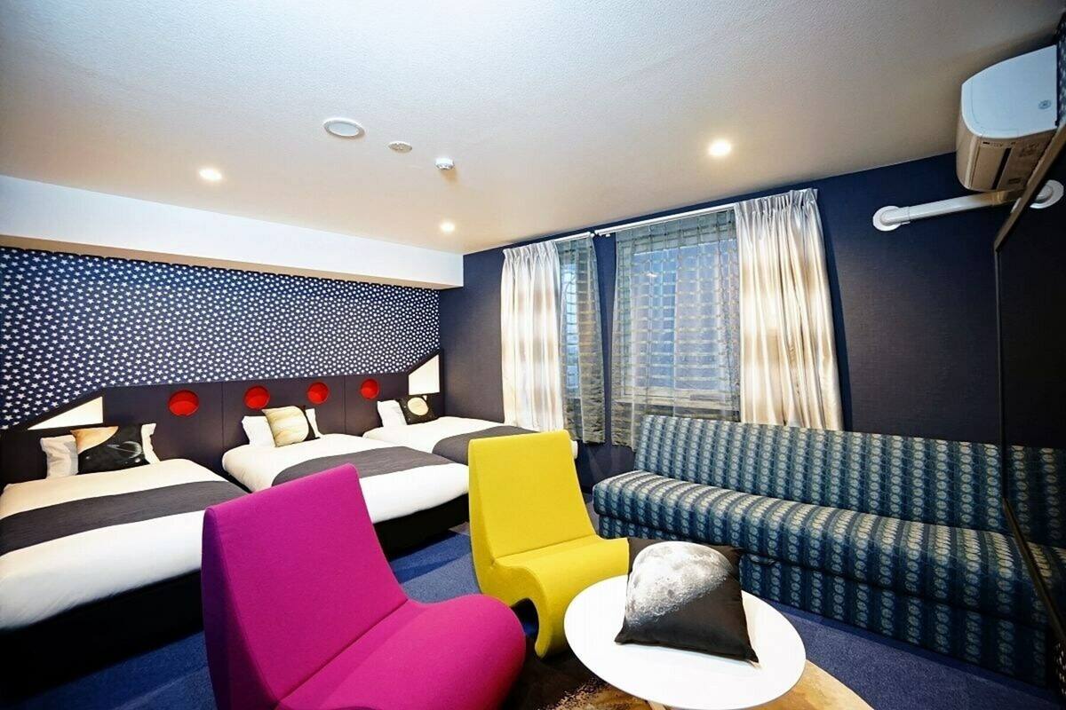 A hotel room with two beds, a sofa, a chair, and a small table.