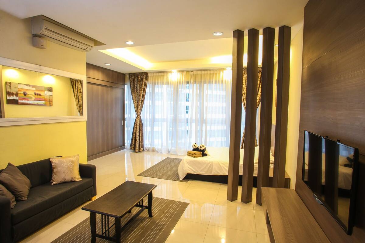 A modern living room with a sofa, coffee table, and a bed with decorative pillows.