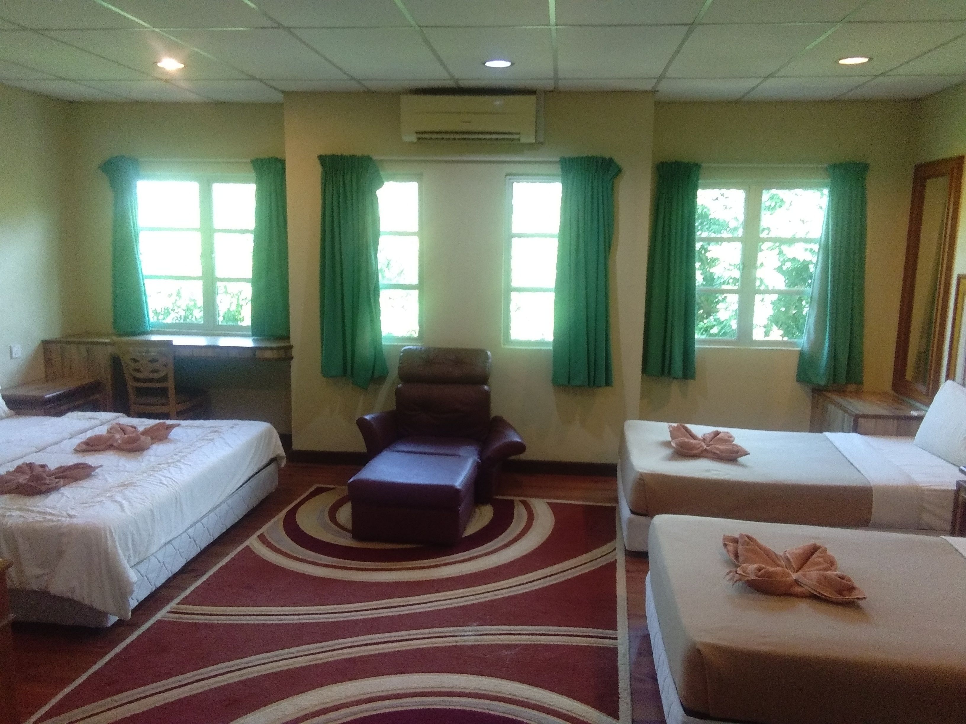 A hotel room with two beds, a sofa, and a desk.