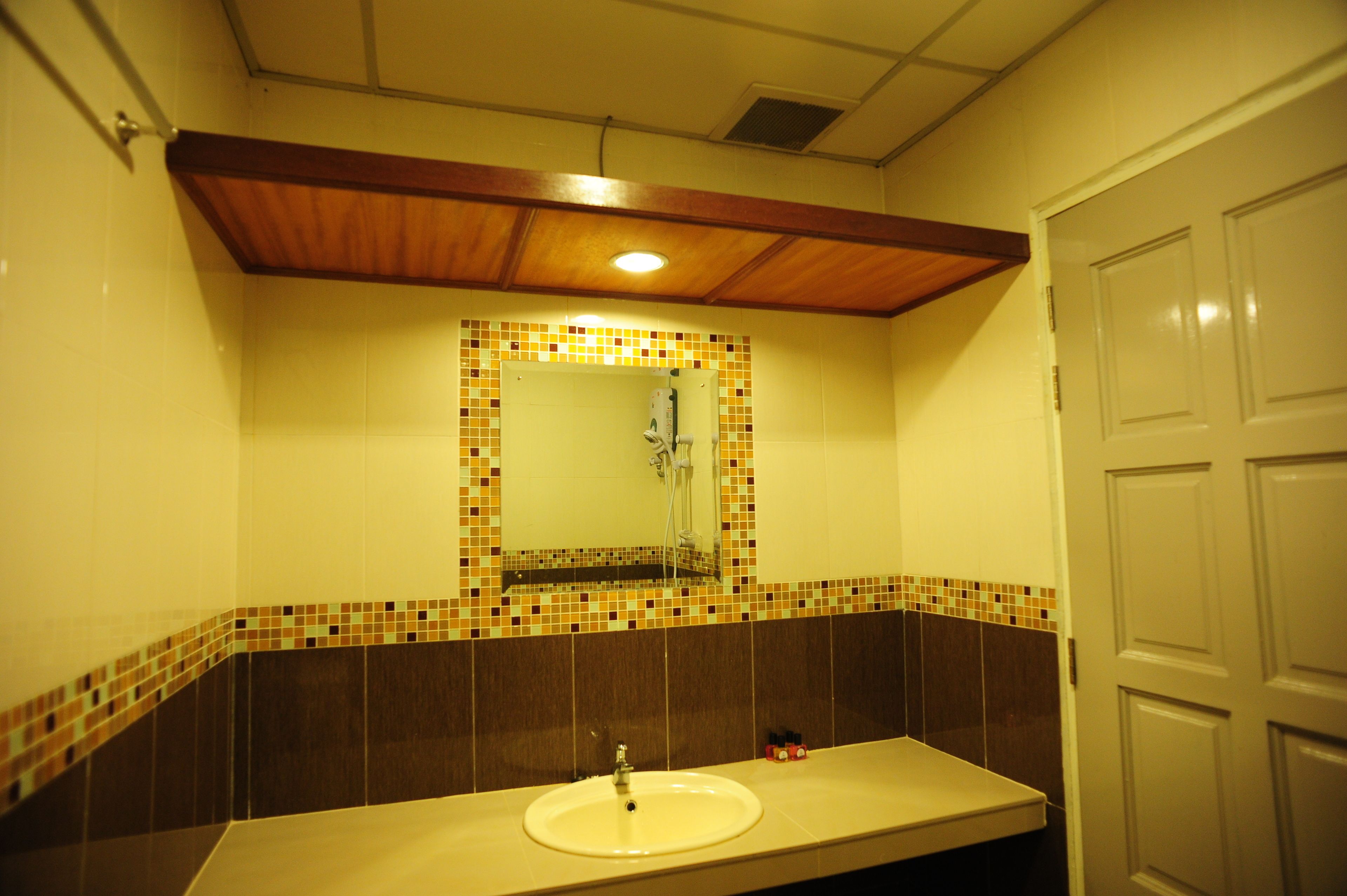 A bathroom with a tiled backsplash, a sink, a mirror, and a door.
