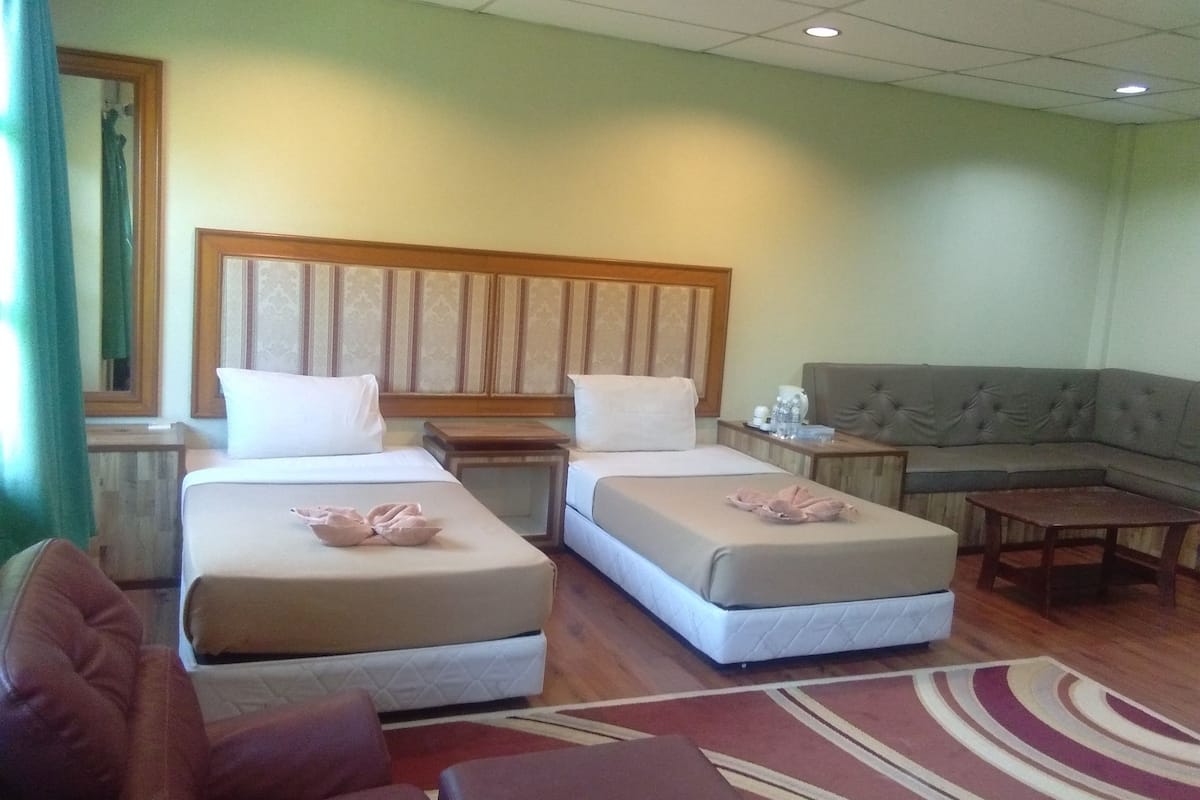 Habitación de hotel con dos camas, un sofá, una mesita y un espejo.