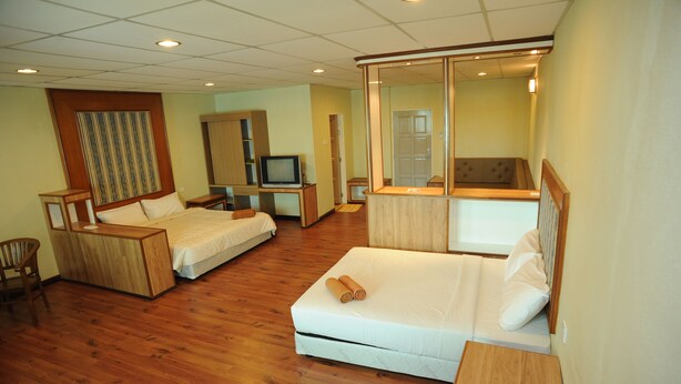 Una habitación de hotel con dos camas, televisión, espejo y muebles de madera.