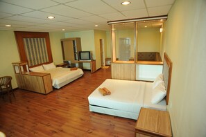 Una habitación de hotel con dos camas, televisión, espejo y muebles de madera.