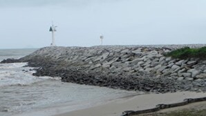Una costa rocosa con una turbina eólica y una boya.