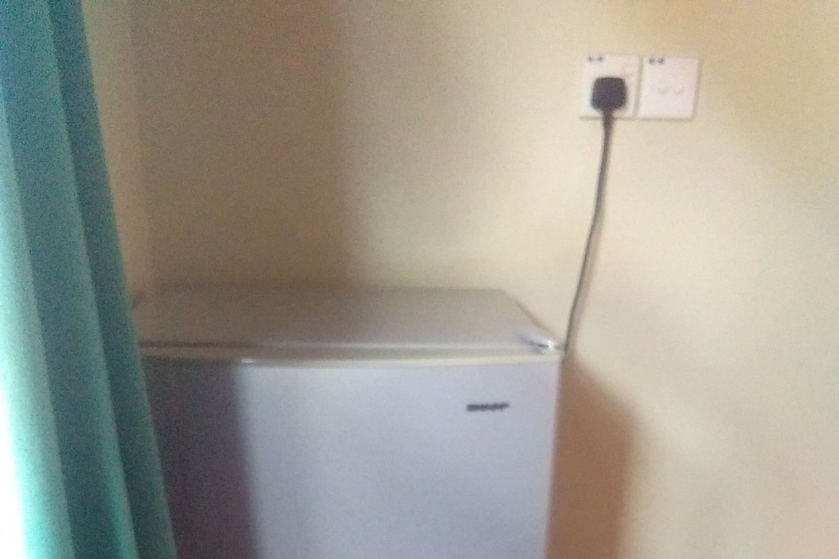 Un refrigerador compacto y moderno con un enchufe en la pared a su lado.