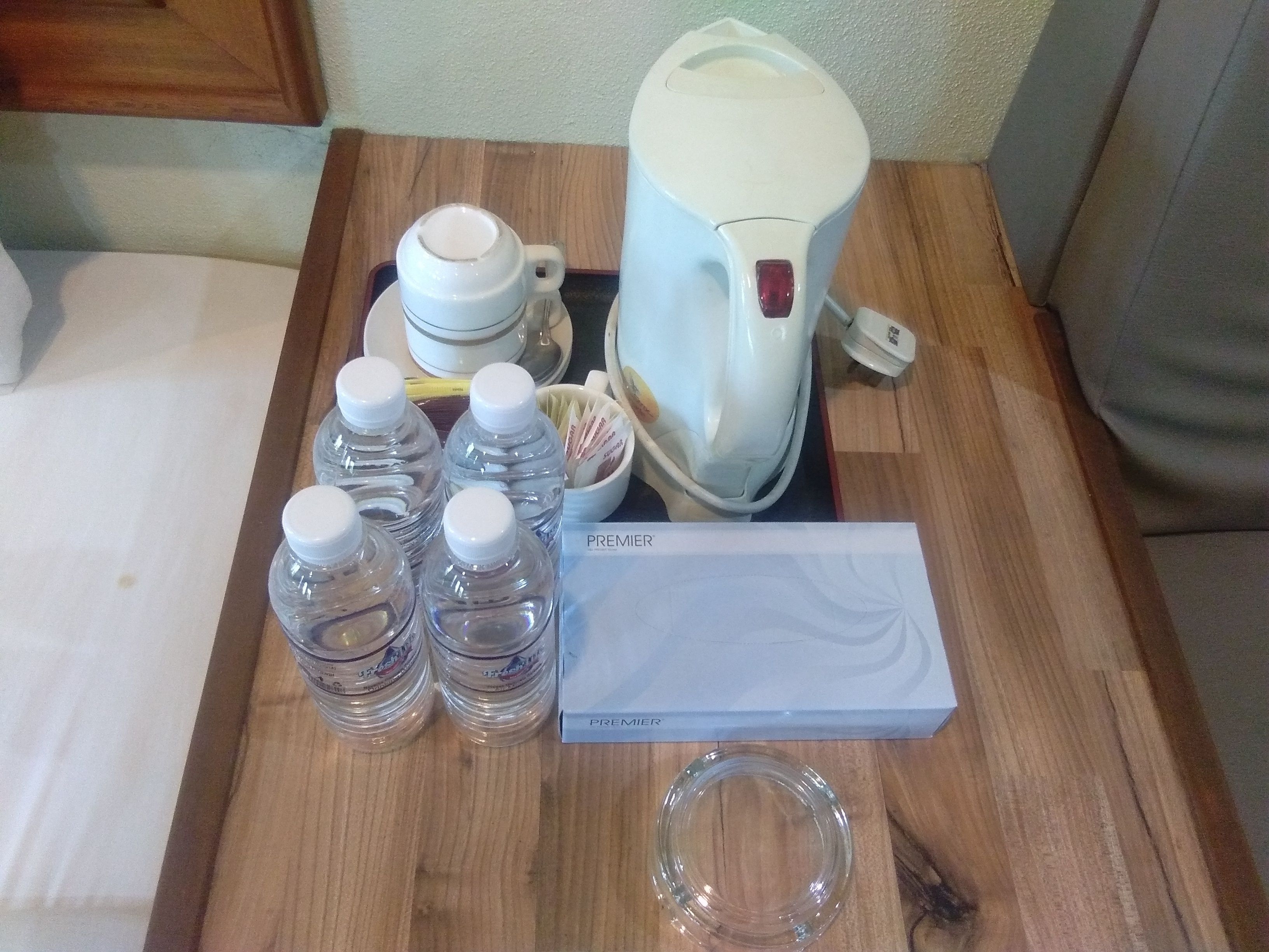 A wooden table with a coffee maker, four water bottles, a glass, and a box labeled "PREMIER".