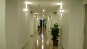 Un largo pasillo bien iluminado con pisos de baldosas y plantas en macetas.