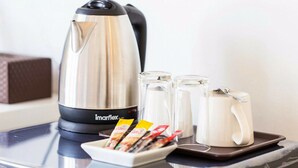 A stainless steel electric kettle, two glass mugs, and a tray with packets of tea and coffee on a car's dashboard. - The Way Phuket Resort (Thep Krasattri)