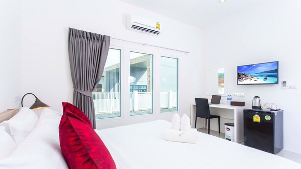 A hotel room with a bed, a desk, a television, and a view of a balcony. - The Way Phuket Resort (Thep Krasattri)