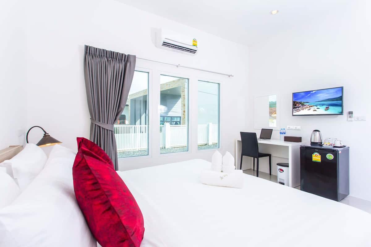 Quarto de hotel com cama, escrivaninha, televisão e vista para uma varanda.