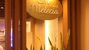 A café sign with a wooden planter and tall plants in front. - Kew Hotel (Tagbilaran)