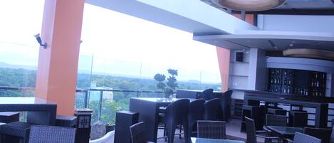 An outdoor seating area with wicker furniture, a bar, and a view of the landscape.