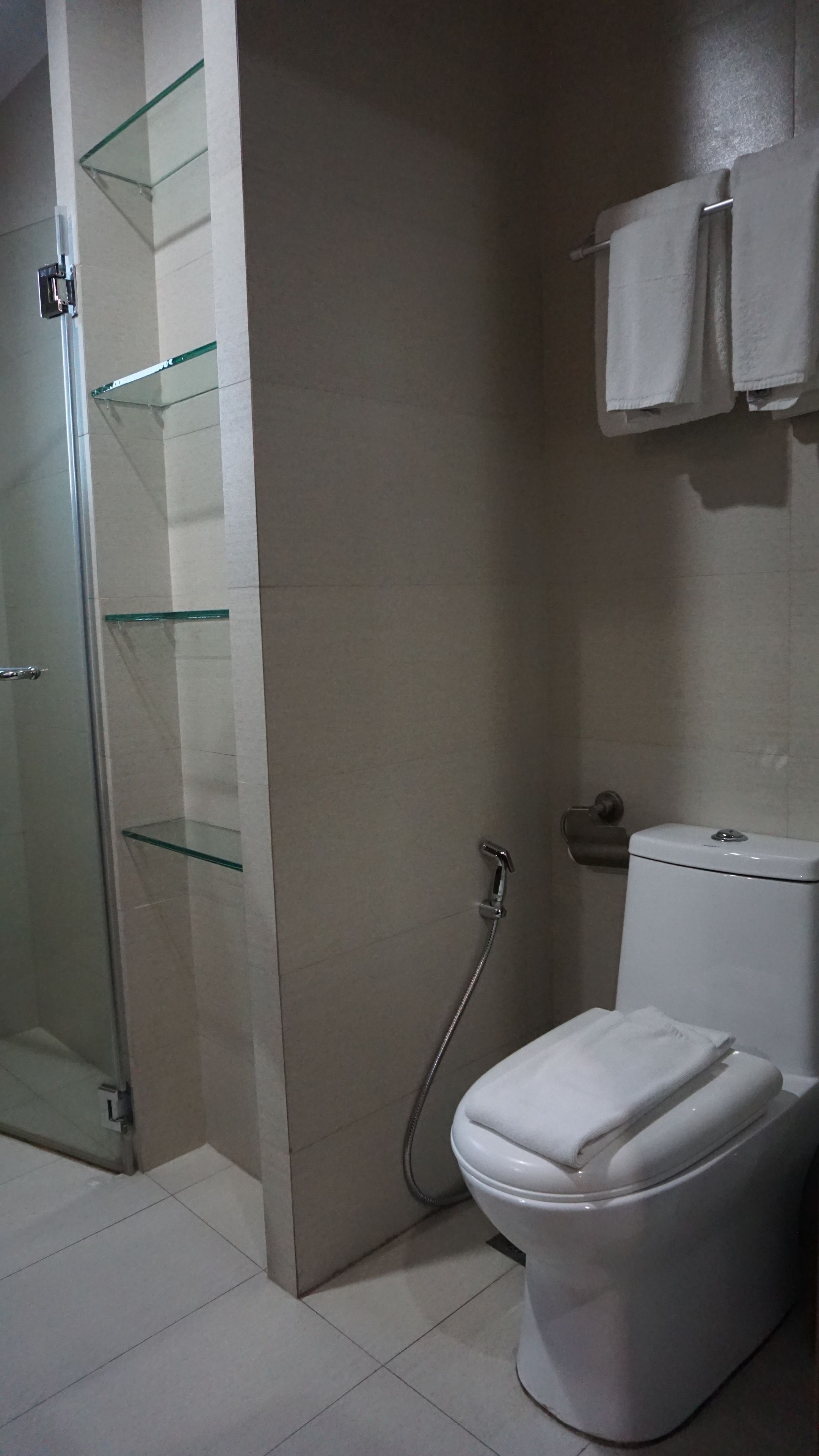 Ein Badezimmer mit Glasdusche, Toilette und Handtuchhalter.