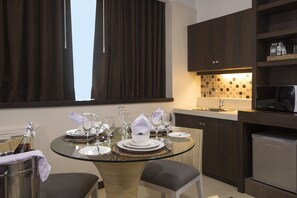 A modern kitchen with dark wood cabinets, a built-in microwave, and a glass dining table set for four. - Kew Hotel (Tagbilaran)