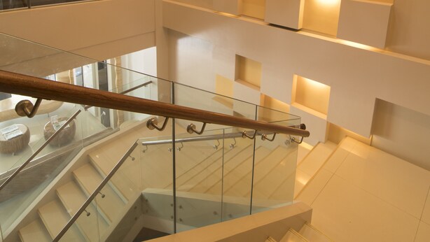 A modern interior with a glass staircase, a woven light fixture, and illuminated wall panels. - Kew Hotel (Tagbilaran)