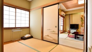 A traditional Japanese room with tatami flooring, sliding doors, a futon bed, a TV, and a small cabinet. - Gorakan (Hakone)