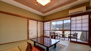 A traditional Japanese room with tatami flooring, a low table, and sliding doors. - Gorakan (Hakone)