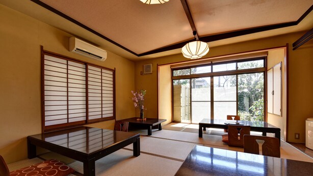 A traditional Japanese room with tatami flooring, sliding shoji doors, and a low table with cushions. - Gorakan (Hakone)
