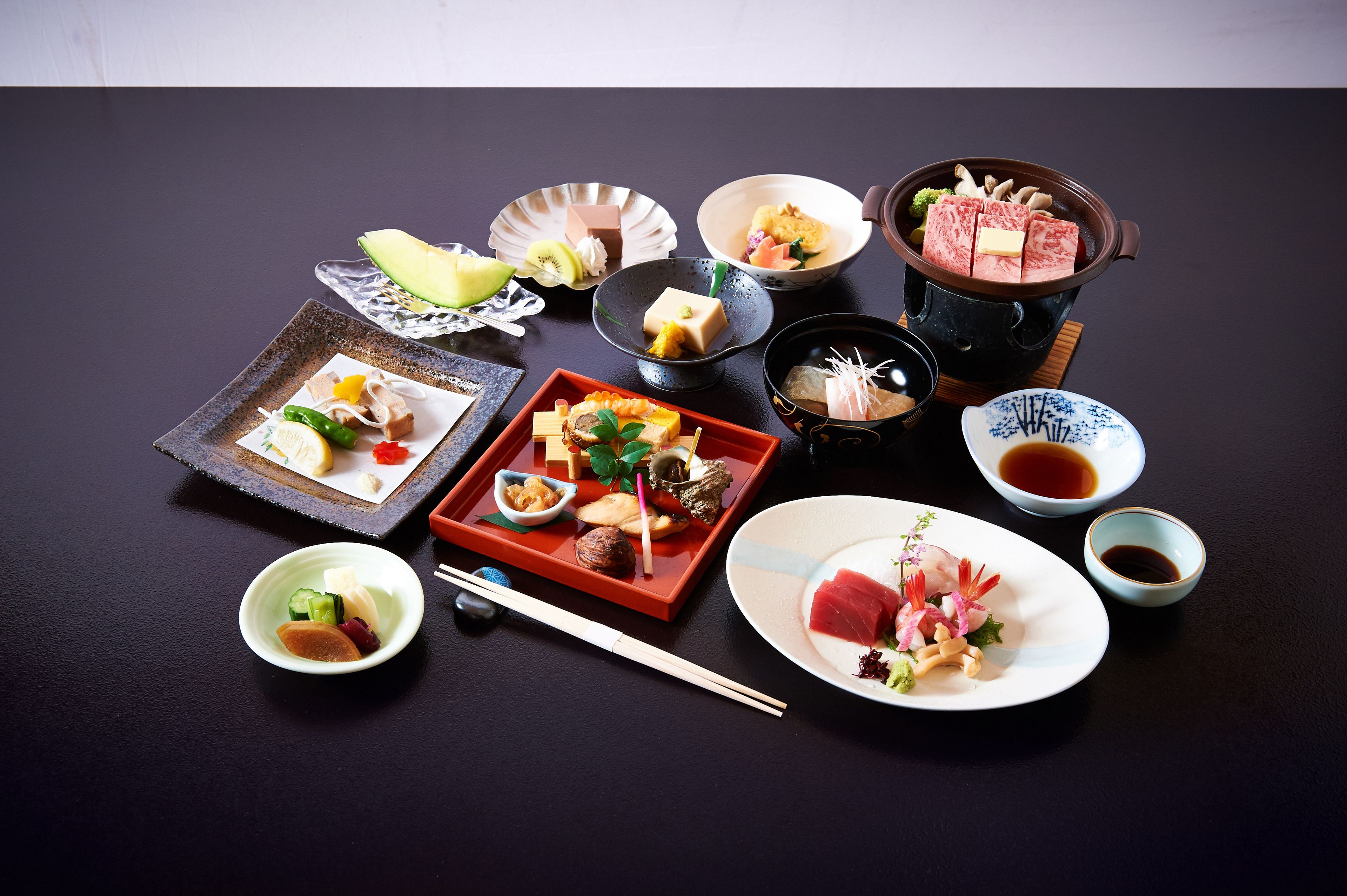A variety of Japanese dishes arranged on a table, including sushi, sashimi, and a hot pot.