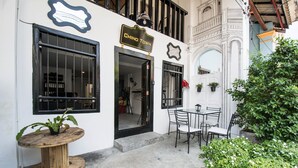 A building with a sign reading "CHINO TOWN" and a small outdoor seating area with a table and chairs. - Chino Town Gallery Alley (Phuket)