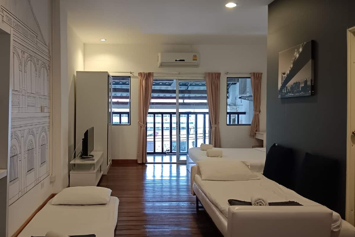 A hotel room with a balcony, a TV, and a painting on the wall.