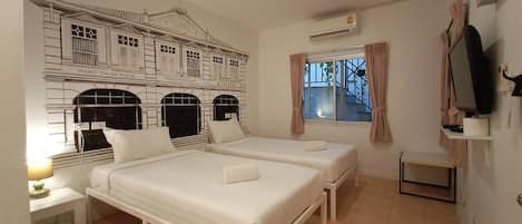 Habitación de hotel con dos camas, una mesita, un televisor y una ventana con cortinas.
