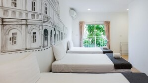 A hotel room with two beds, a large mural of a building, a window with a view of greenery, and a small balcony. - Chino Town Gallery Alley (Phuket)