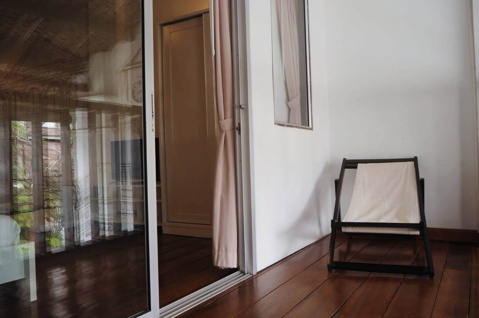 A room with a wooden floor, a sliding glass door, a small chair, and a framed picture on the wall.
