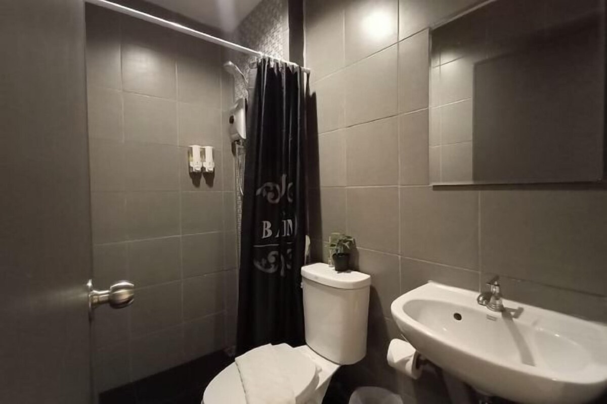 Un baño con inodoro, lavamanos y cortina de ducha.