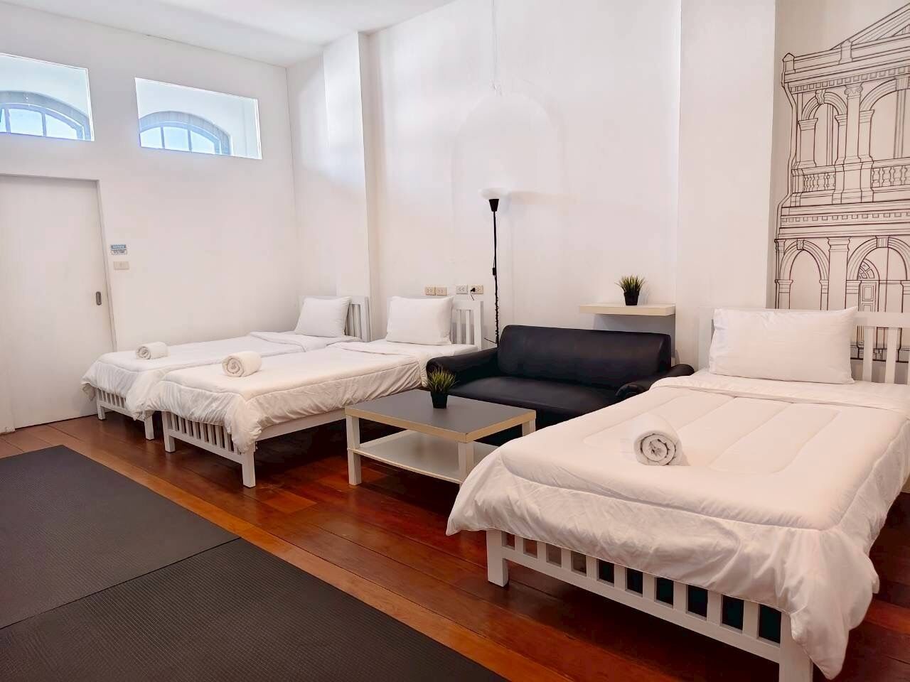 A room with two beds, a sofa, a coffee table, and a lamp.