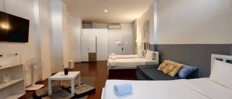 Une chambre d’hôtel moderne équipée d’un grand lit, d’un canapé, d’une petite table, d’une télévision et d’une armoire.