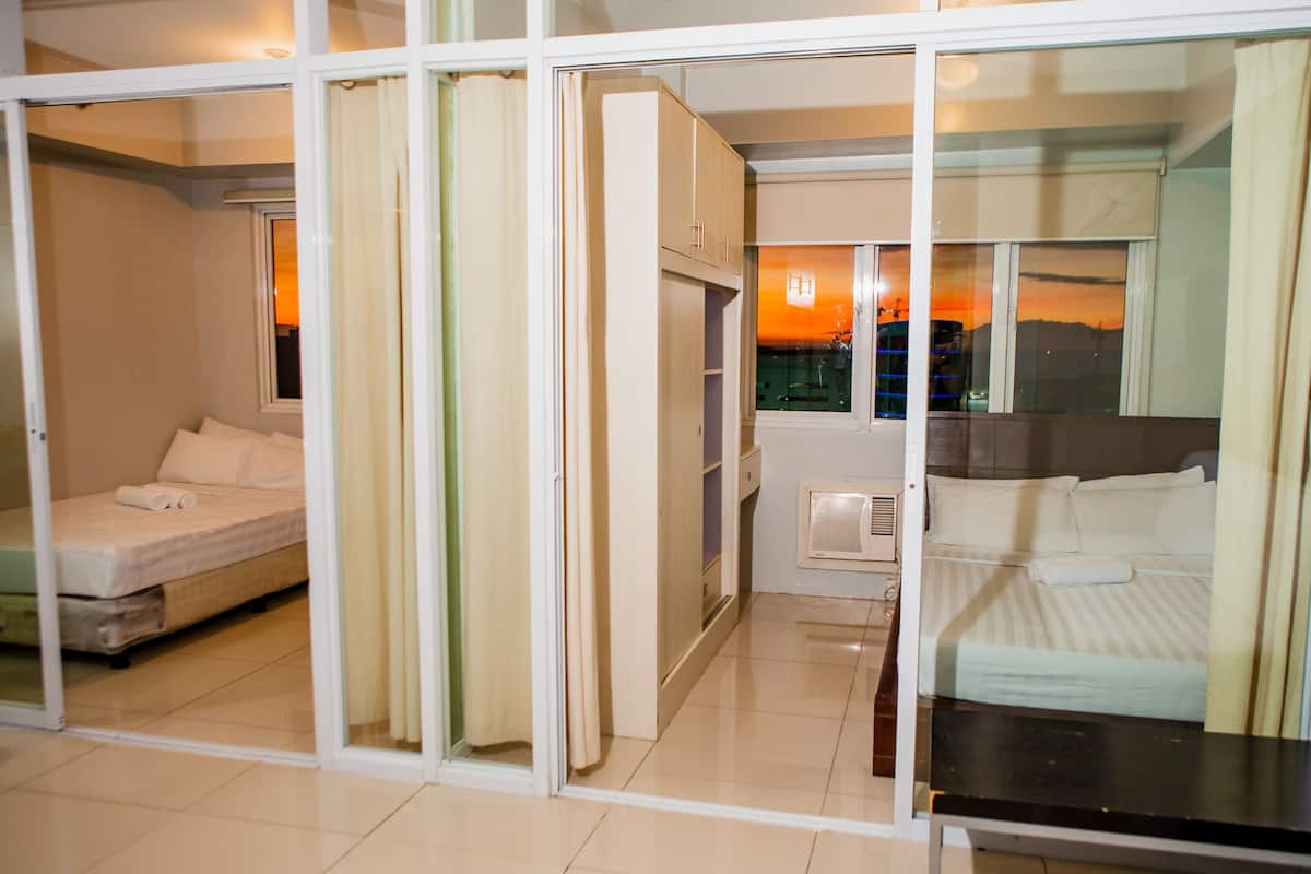A hotel room with two beds, a sliding glass door, and a view of a sunset.