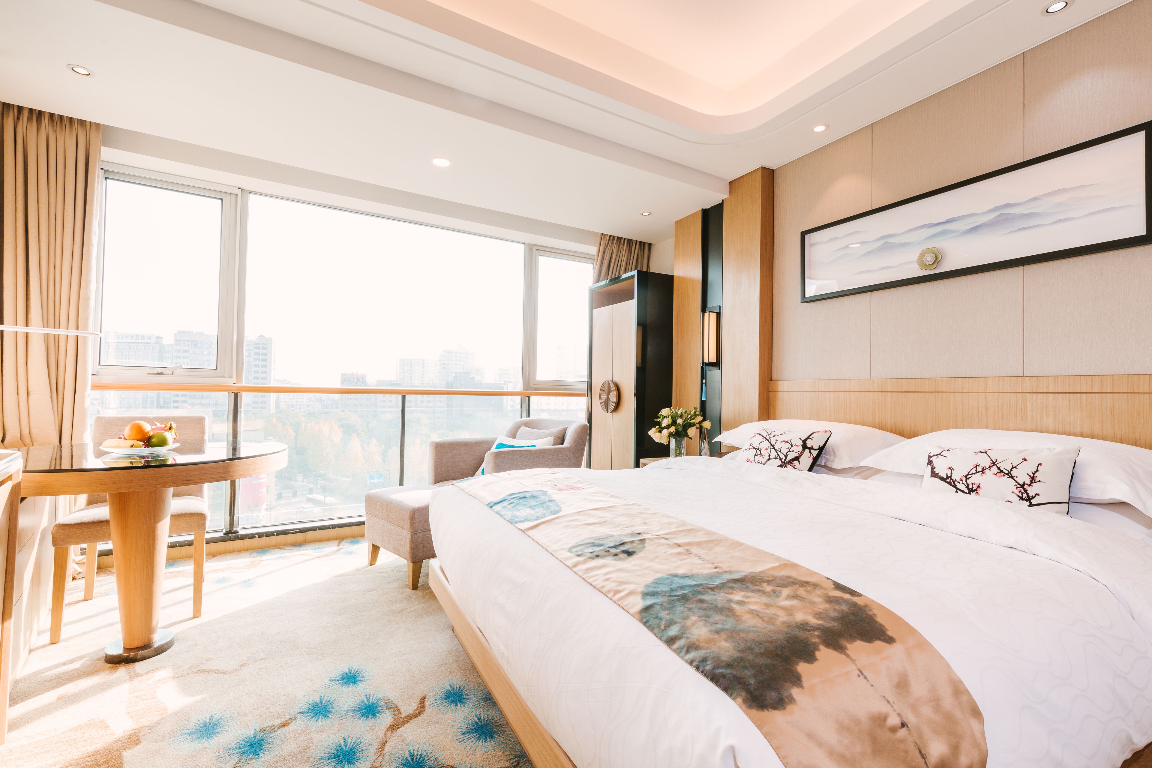 A hotel room with a large bed, a desk, and a view of the city.