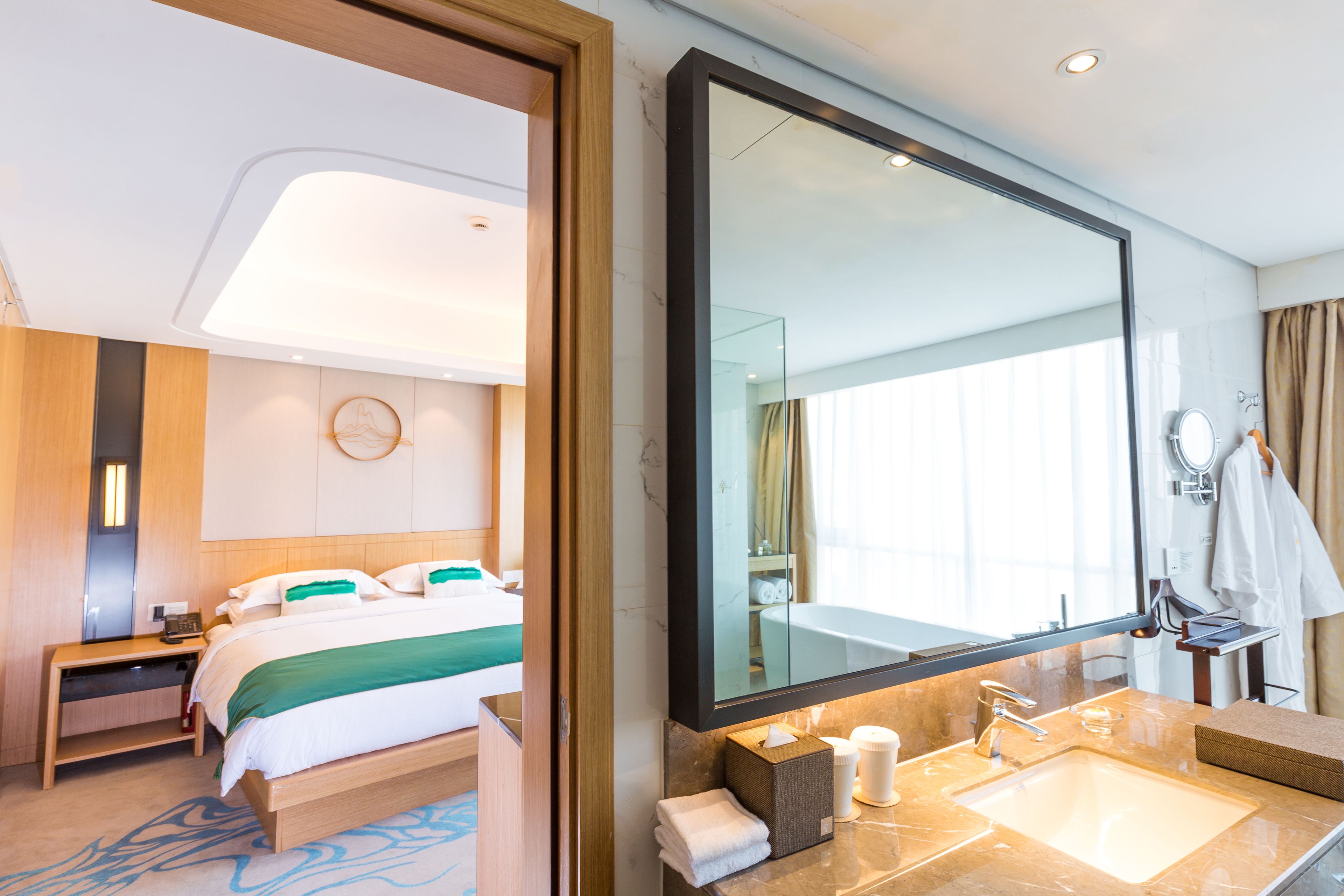 Una habitación de hotel con una cama grande, un baño con espejo, lavamanos y toallero.