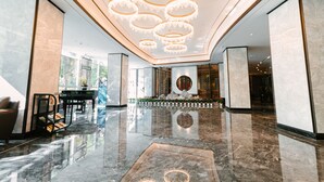 A spacious lobby with a reflective marble floor, a central seating area with a piano, and a decorative wall with a circular motif. - Nade Hotel (Hangzhou)