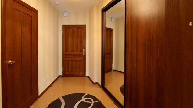 A hallway with wooden doors, a carpeted floor, and a ceiling light fixture. - Voyage Hotel (Minsk)